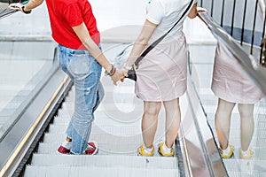 young woman friends on escalator in shopping mall