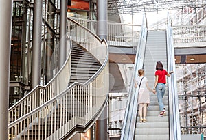 Young woman friends on escalator in shopping mall