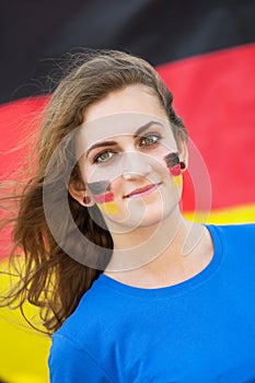 Happy young woman with German flag on cheeks on the background