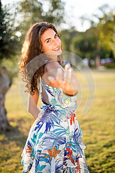 Happy young woman gesturing at park, romantic in evening sun.