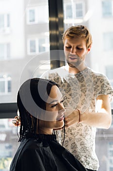 Happy young woman getting a new haircut by hairdresser at parlor