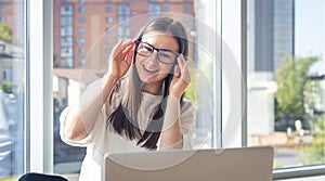 Happy young woman in glasses in front of a laptop screen.