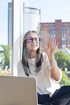 Happy young woman in glasses in front of a laptop screen.