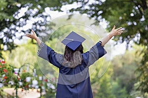 Happy young woman graduating with hands up