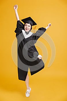 Happy young woman in graduation gowns dancing for celebration