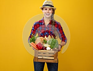 Happy young woman grower with box of fresh vegetables