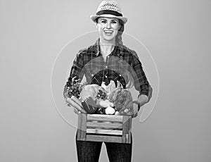 Happy young woman grower with box of fresh vegetables