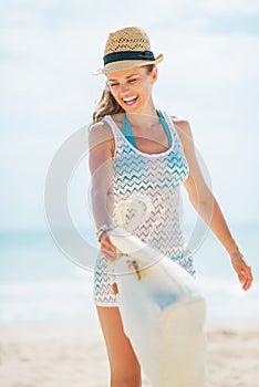 Happy young woman in hat and with bag having fun time on beach