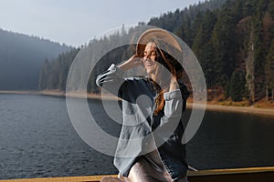 Happy young woman in hat enjoys lake view in forest. Relaxing moments. stylish girl enjoys the freshness outdoor