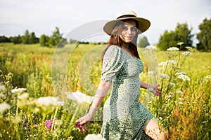 Happy young woman in a hat walks in the field