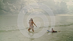 Happy young woman having fun with her little kids in the ocean water at the Panama City Beach USA