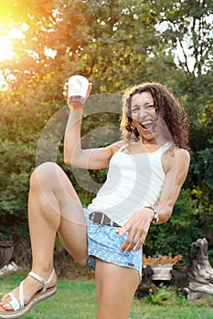 Happy young woman having fun at summer party drinking cocktail at sunset