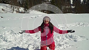 Happy young woman having fun throwing snow. She is laughing. A girl is walking in the winter forest on nature in the