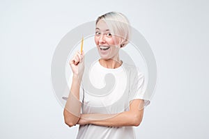 Happy young woman having idea and looking at the camera holding pencil.