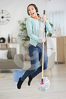 happy young woman in headphones with mop cleaning floor