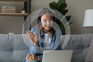 Happy young woman in headphones say hi making video call