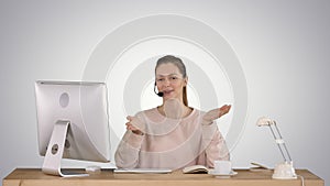 Happy young woman in headset looking at camera and talking on gradient background.