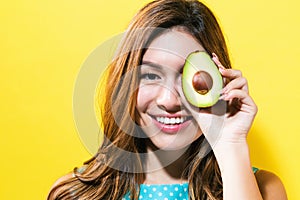 Happy young woman holding avocado halve