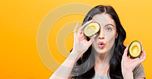 Happy young woman holding avocado halves