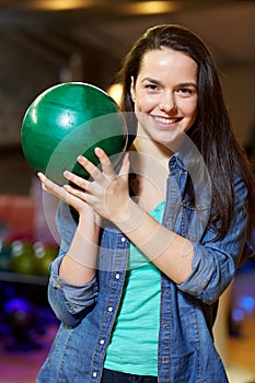 Happy young woman holding ball in bowling club
