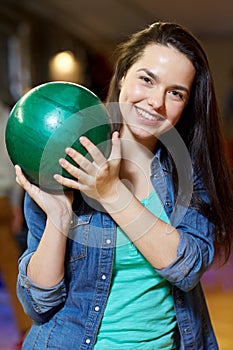 Happy young woman holding ball in bowling club