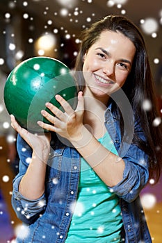 Happy young woman holding ball in bowling club