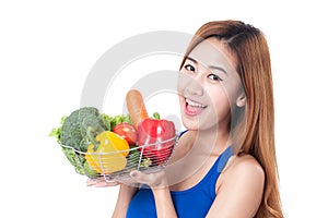 Happy young woman holding basket of vegetables.