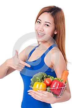 Happy young woman holding basket of vegetables.