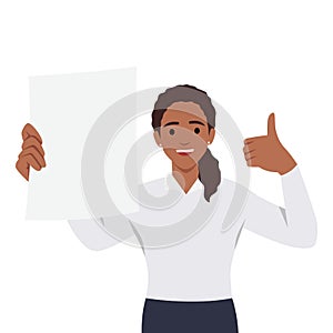 Happy young woman holding a blank or empty sheet of white paper or board and gesturing thumbs up sign