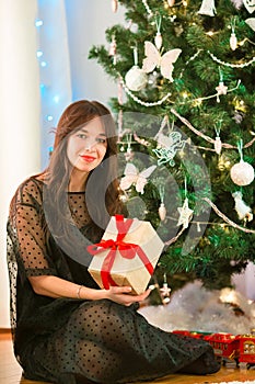 Happy young woman holding christmas present box on Christmas eve