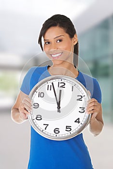 Happy young woman holding clock