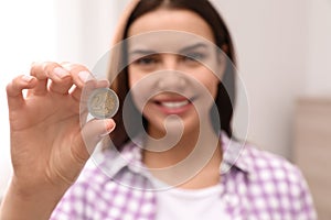 Happy young woman holding coin, focus on hand