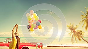 Happy young woman holding colorful balloons with floating