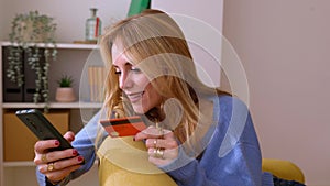 Happy young woman holding credit card while shopping online at home