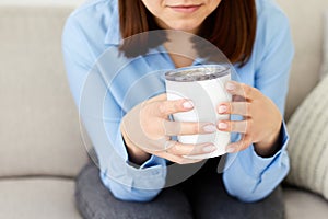 Dreaming girl sitting in living room with cup of hot coffee enjoying the rest