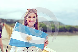 Happy young woman holding flag of Argentina graded