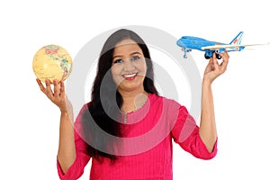 Happy young woman holding globe and toy plane