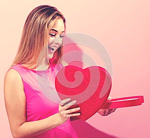 Happy young woman holding heart shaped box