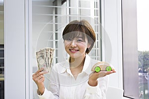 Happy young woman holding Japanese Yen and toy car