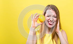 Happy young woman holding a lemon