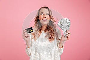 Happy young woman holding money and credit card.