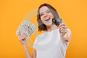 Happy young woman holding money and credit card.