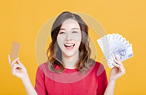 Happy young woman holding money and credit card