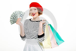 Happy young woman holding money dollars and shopping bags