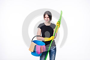 Happy young woman holding a mop and a bucket filled with cleaning products isolated on white background