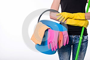 Happy young woman holding a mop and a bucket filled with cleaning products isolated on white background