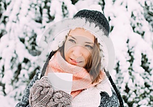 Happy young woman holding mug of tea winter snowy