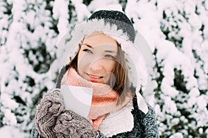 Happy young woman holding mug of tea winter snowy