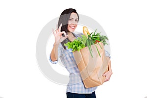 Happy young woman holding paper bag with groceries