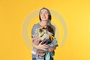 Happy young woman holding pile of dirty laundry